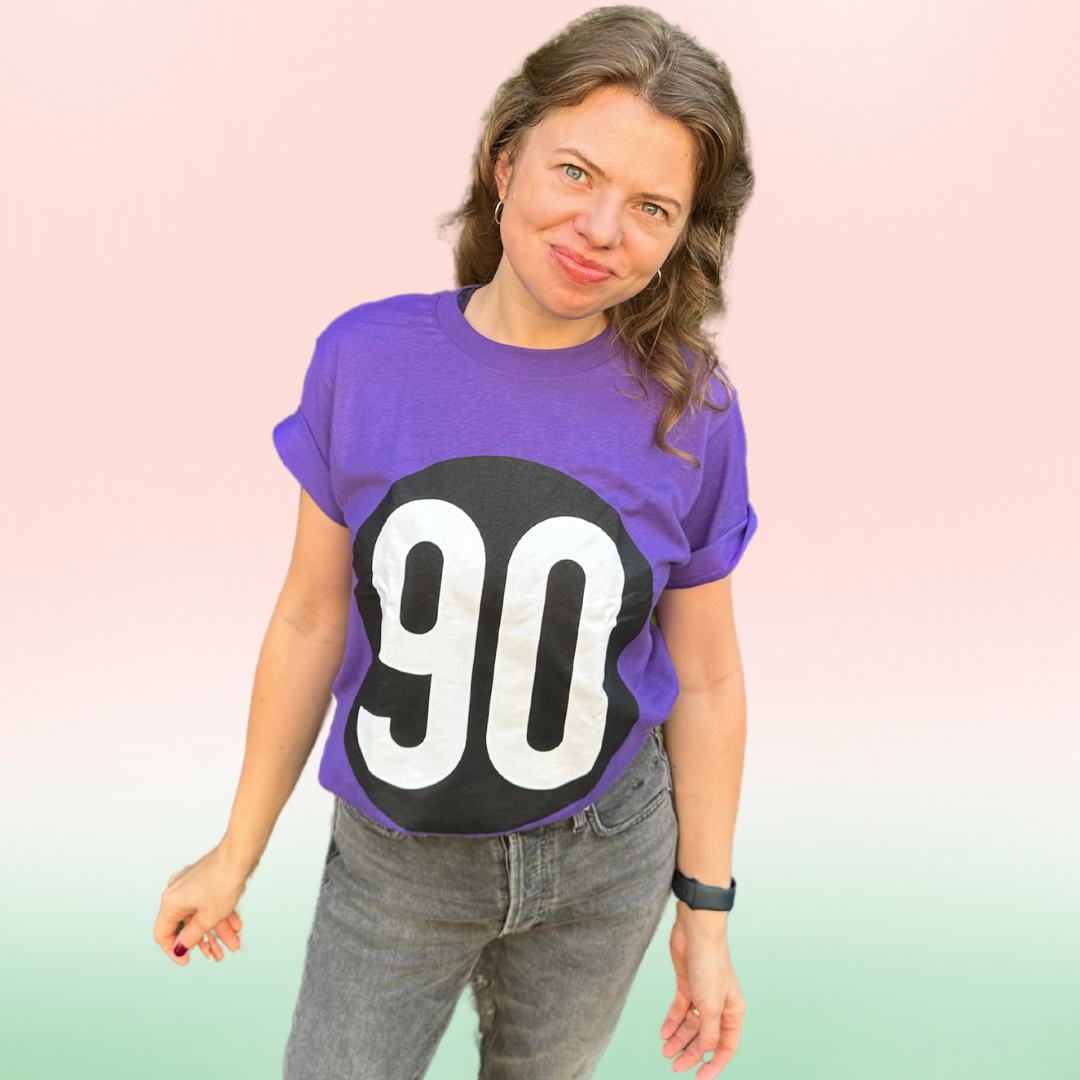 Confident woman posing in 90 The Original Signature Purple Tee with a striking '90' front logo design