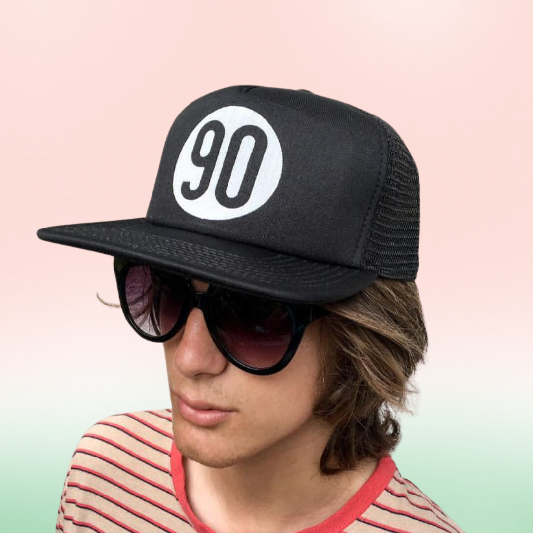 Stylish individual wearing the 90 The Original Trucker Hat with a bold logo on the front.