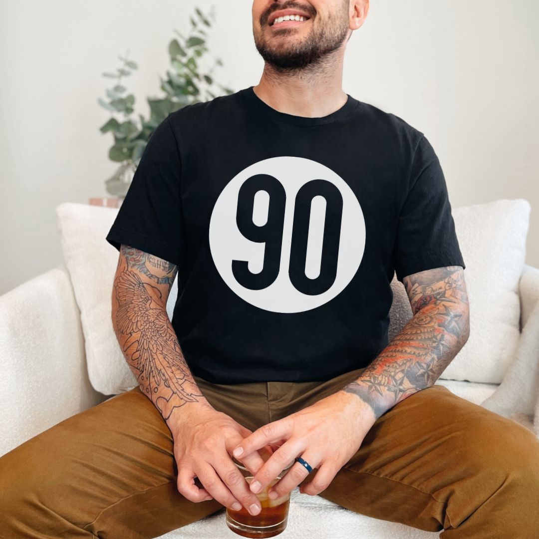Content man relaxing in a black 90 The Original tee, a nod to casual comfort with a vintage flair.
