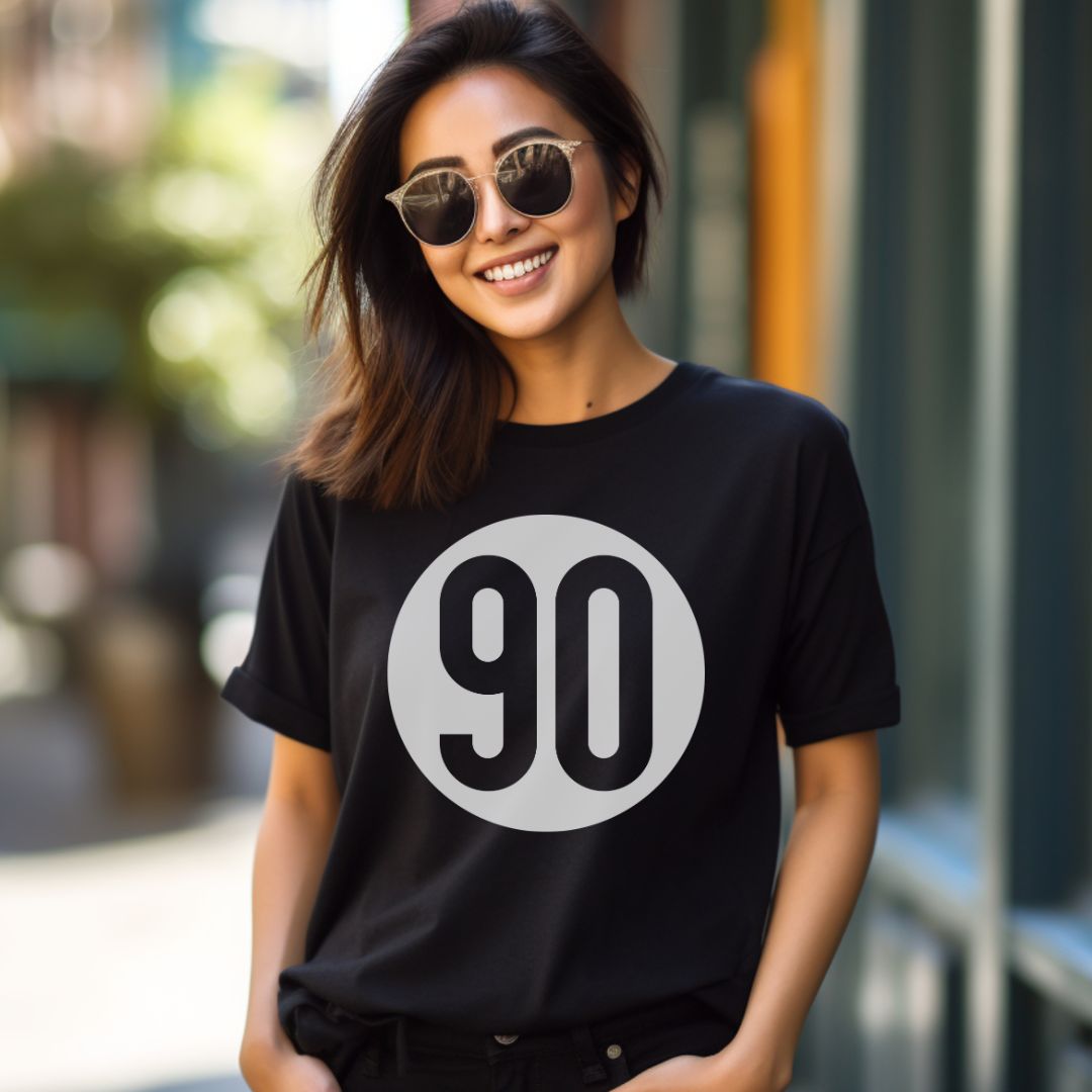 Trendy woman showcasing the 90 The Original black tee with a distinctive 90 logo on a city backdrop.