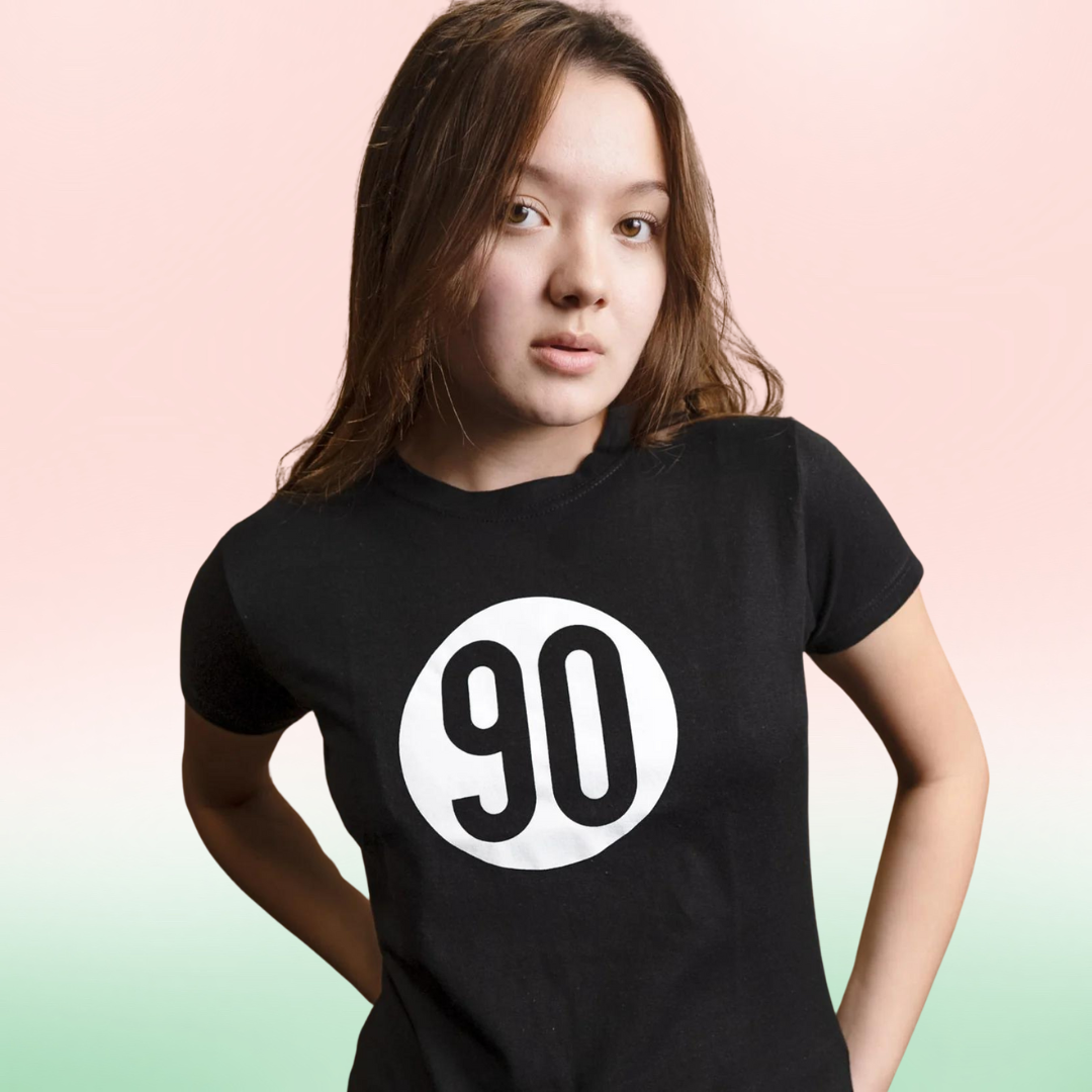 Young woman wearing the 90 The Original Women's Black Tee, confidently showcasing the white '90' logo